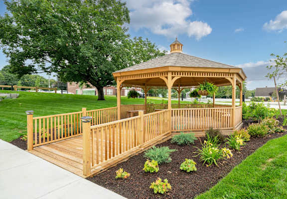 A wooden gazebo is surrounded by a wooden fence and plants.