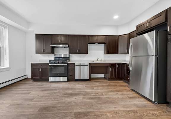 A modern kitchen with dark brown cabinets and stainless steel appliances.