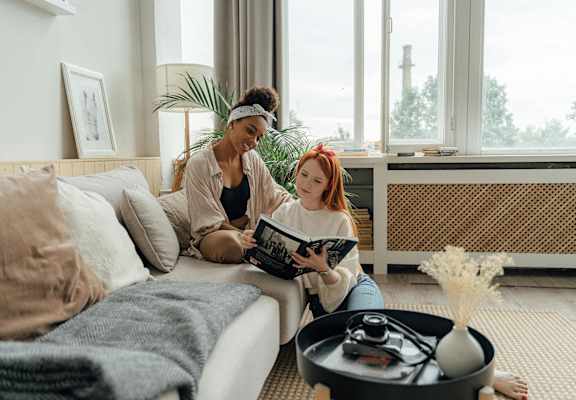 two women sitting on a couch reading a book