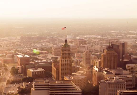 A cityscape with a tall building featuring a flag on top.