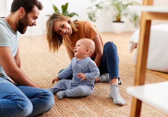 Mother and Father Smiling while Playing with Baby