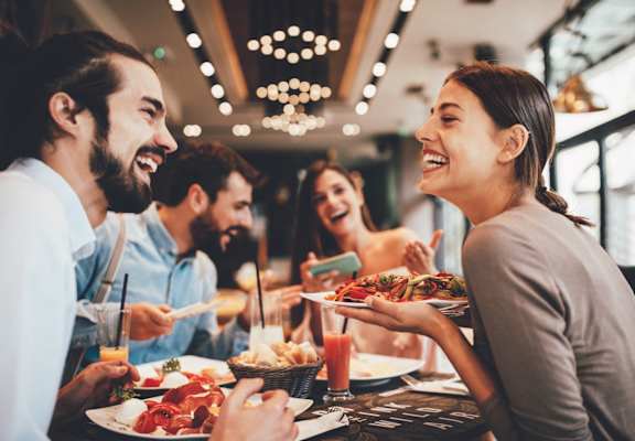 Friends Smiling while Having Food and Drinks Together