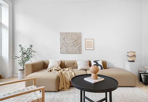 A living room with a beige couch, a coffee table, and a painting on the wall.