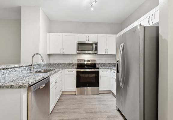 kitchen with custom white cabinetry, granite countertops, and stainless steel appliances at Sorelle apartments