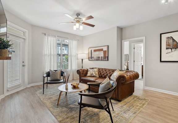 spacious living room with a lighted-ceiling fan and expansive windows at Sorelle apartments