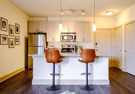 a photo of a kitchen island with barstools and kitchen in the background
