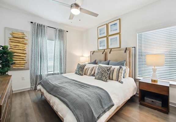A bedroom with a large bed and a ceiling fan.