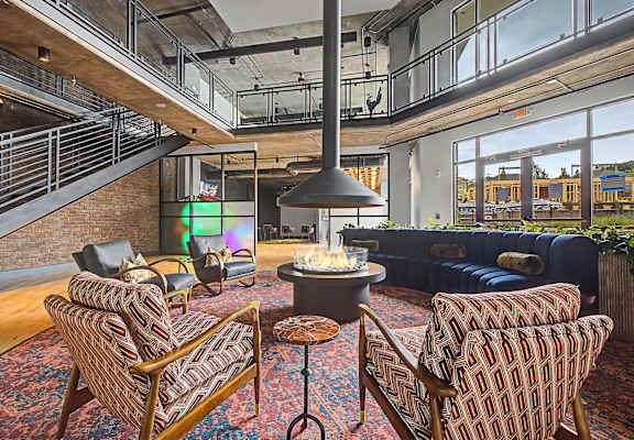 A living room with a couch, chairs, and a table with a fireplace.