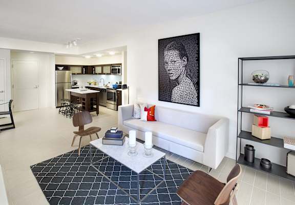 a living room and kitchen with a white couch and a rug