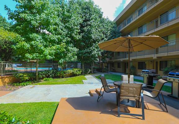 A patio with chairs and an umbrella is in front of a building at Bixby Knolls, Long Beach, CA