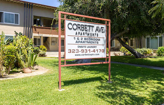 A sign for Corbett Ave Apartments stands in front of a building.