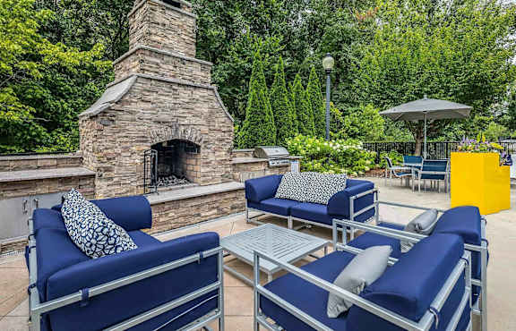 A patio with blue couches and a stone fireplace.