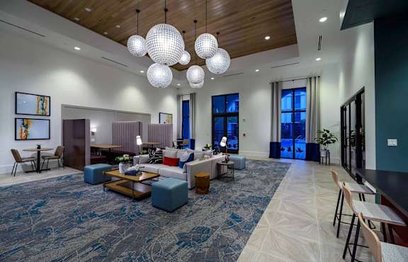 A large, open living room with a long carpeted hallway and a variety of seating options.