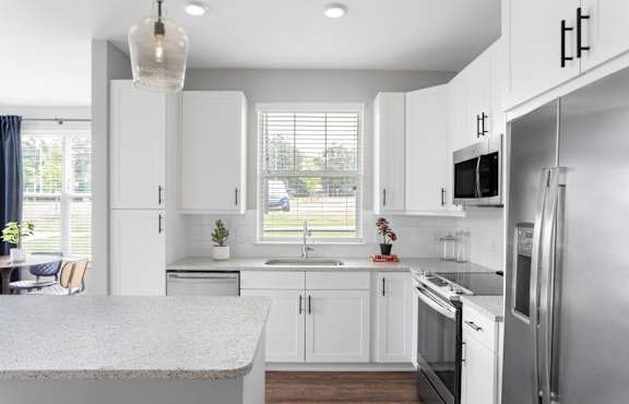 A modern kitchen with white cabinets and stainless steel appliances.