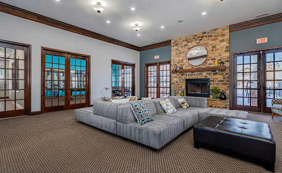 A living room with a grey couch and a stone fireplace.