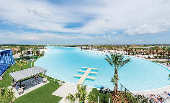 a large swimming pool with palm trees and a water slide