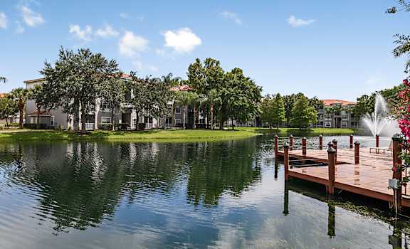 a lake with a dock and a fountain in front of a building