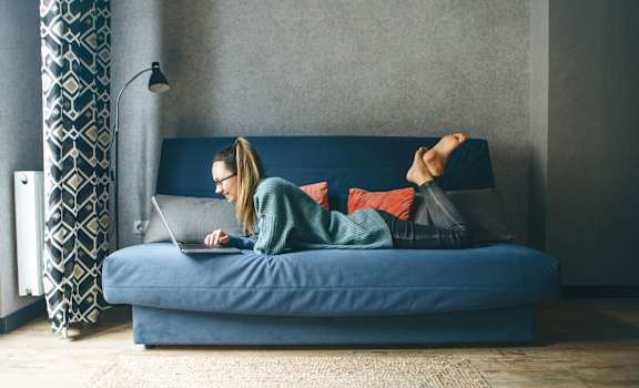 a woman laying on a bed using a laptop computer Pineview Apartments in Clearwater, FL 33755