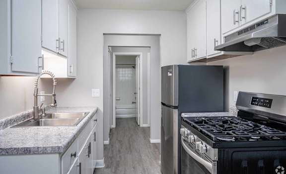 A kitchen with a black stove top oven and a refrigerator.