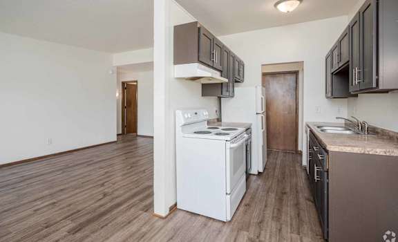 A kitchen with white appliances and brown cabinets.