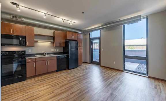 an empty living room with a kitchen and a sliding glass door