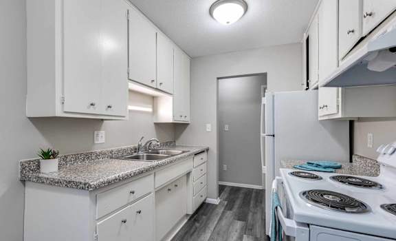 A kitchen with white cabinets and a granite countertop.