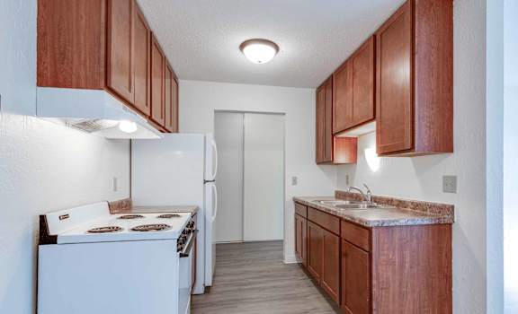 A kitchen with white appliances and wooden cabinets.
