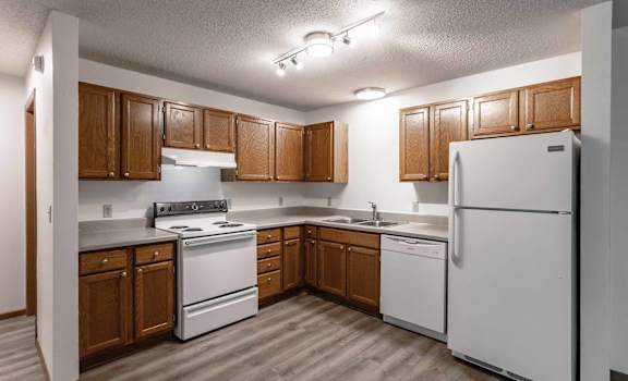 A kitchen with white appliances and wooden cabinets.
