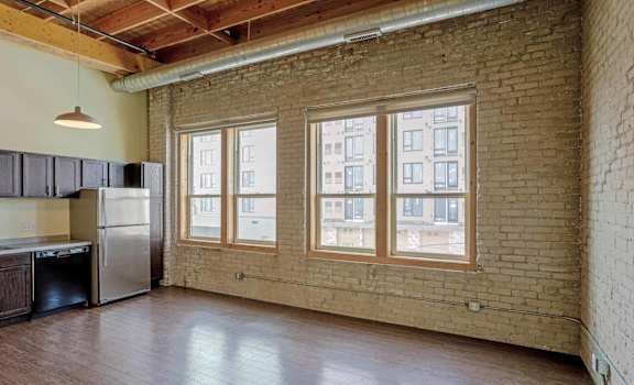 an empty living room with brick walls and a large window