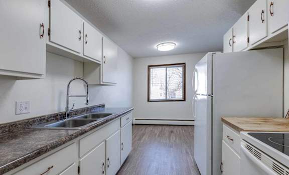 A kitchen with white cabinets and a window.
