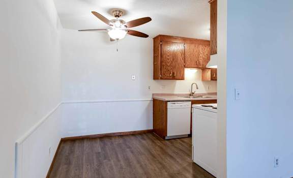 A kitchen with a white wall and a ceiling fan.