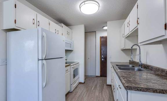 A kitchen with white appliances and cabinets.
