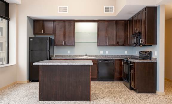 A kitchen with dark brown cabinets and black appliances.