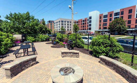 a patio with a firepit and benches in front of a building