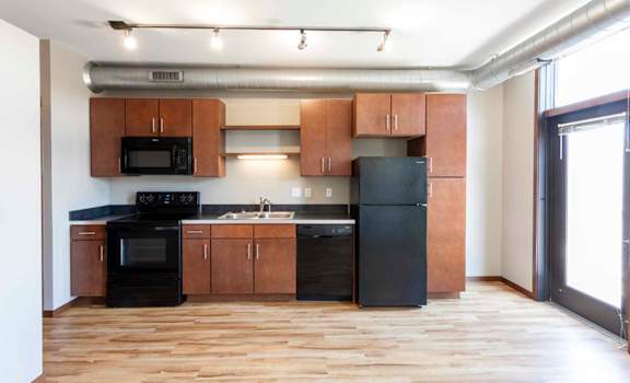 an empty kitchen with wooden cabinets and black appliances