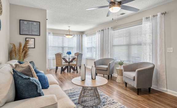 A living room with a beige sofa, a coffee table, and a ceiling fan.