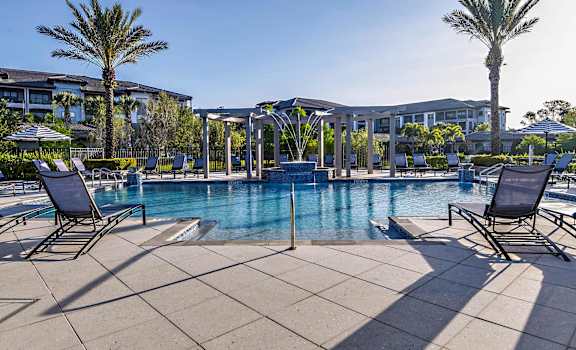 a large swimming pool with chairs and palm trees
