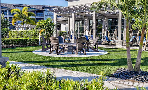 a patio with tables and chairs and a pavilion with palm trees