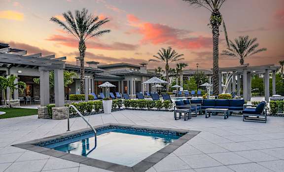 a pool with blue chairs and a sunset in the background