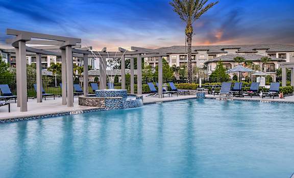 a resort pool with chairs and a palm tree