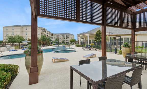 outdoor patio with corn hole game and shaded dining area at Retreat at Wylie senior 55+ apartments