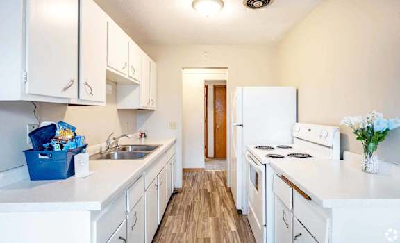 A kitchen with white appliances and cabinets.