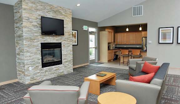 A living room with a stone fireplace and grey couches.