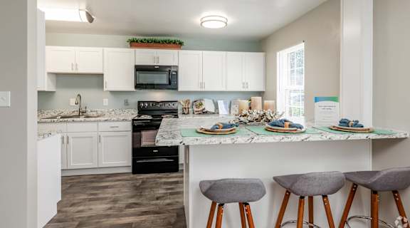 A kitchen with a marble countertop and bar stools.