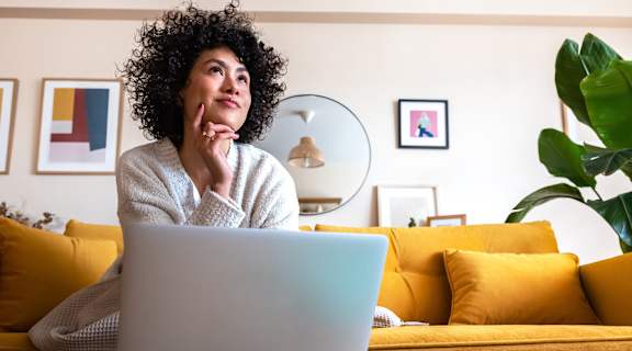 A person with curly hair is sitting in front of a laptop.