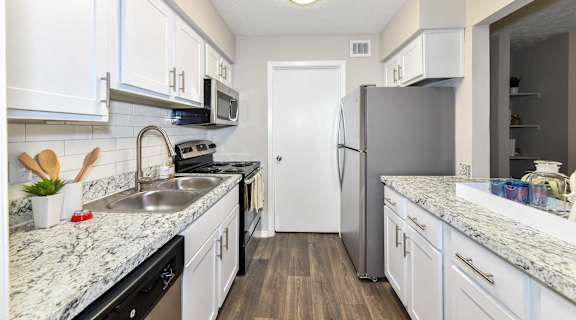 A kitchen with white cabinets and a marble countertop.