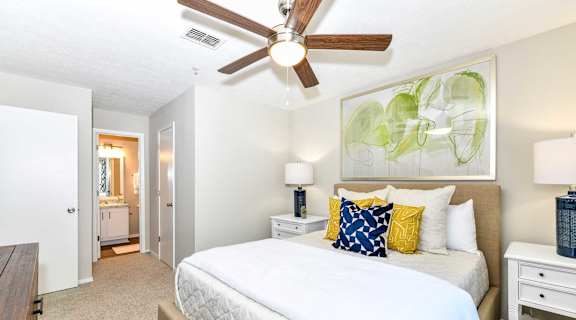 A bedroom with a large bed and a ceiling fan.