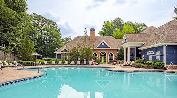 A large swimming pool in front of a house with a blue roof.