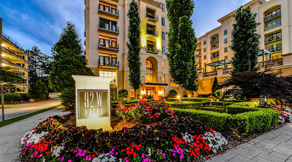a sign and flowers in front of an apartment building