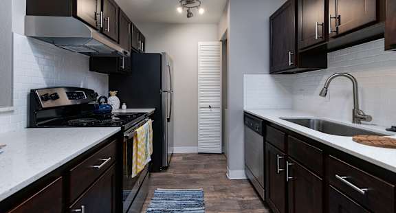 A kitchen with dark brown cabinets and a white counter top.